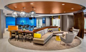 a modern , spacious lounge area with a large sectional couch , dining table , chairs , and bar stools at SpringHill Suites Long Island Brookhaven