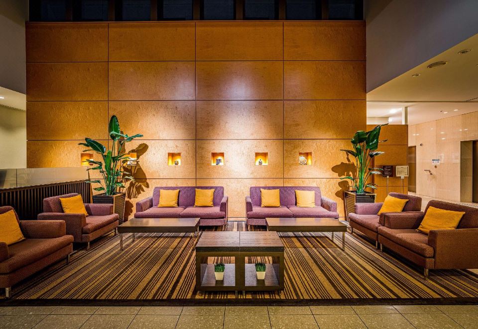 a modern lobby with purple and yellow furniture , wooden paneling , and large windows , creating a cozy atmosphere at Mitsui Garden Hotel Okayama