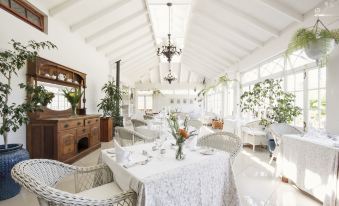 a white dining room with a table set for a meal , surrounded by potted plants at Schoone Oordt Country House