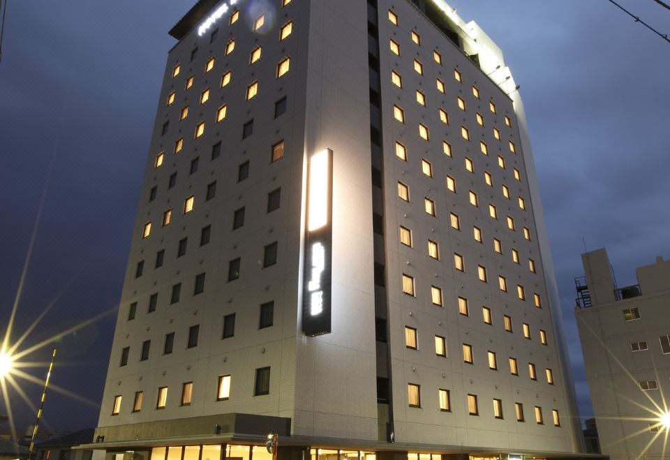 a tall hotel building in a city , illuminated at night , with multiple floors and balconies at Dormy Inn Mishima