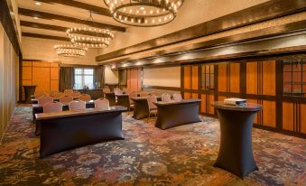 a large conference room with multiple rows of chairs and tables , surrounded by chandeliers and curtains at The Craftsman Inn & Suites
