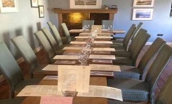 a long dining table set for a meal , with multiple chairs arranged around it , creating a pleasant atmosphere at The Anchor Inn