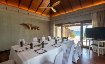 a long dining table set up for a formal event , with white chairs and napkins arranged neatly on the table at Anantara Rasananda Koh Phangan Villas