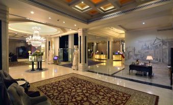 The hotel features a spacious lobby with a beautifully decorated ceiling and elegant chandeliers at Espinas International Hotel