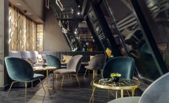 a modern cafe with gold and black furniture , including chairs and tables , arranged around a central area at Hilton Gdansk