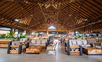 a large wooden building with a thatched roof , featuring a seating area with chairs and couches at Hotel Campestre las Camelias