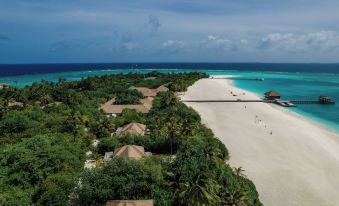 aerial view of a sandy beach with palm trees , white sand , and a few boats in the water at Noku Maldives
