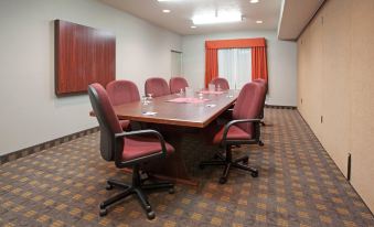 a conference room with a wooden table , red chairs , and a window covered by curtains at Home2 Suites by Hilton Ogden