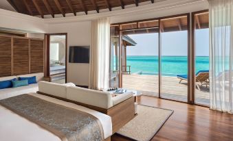 a spacious bedroom with a king - sized bed and a large window overlooking the ocean , providing a serene and tranquil atmosphere at Anantara Dhigu Maldives