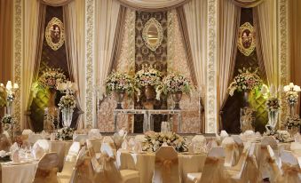 a luxurious banquet hall decorated for a wedding , with white and gold decorations , flowers , and gold tablecloths at Holiday Inn Jakarta Kemayoran, an IHG Hotel
