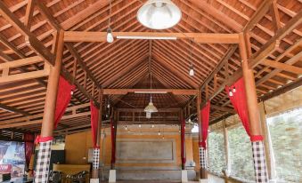 a large wooden structure with a high ceiling and red pillars is shown in the image at Ubud Hotel & Cottages