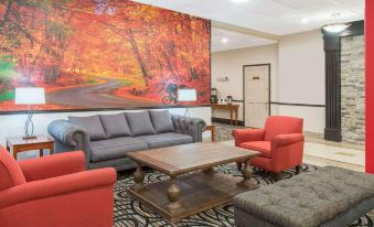 a living room with a couch , chairs , and a coffee table in front of a large painting at Ramada by Wyndham Cumberland Downtown