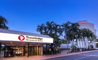 "a large building with a sign that says "" travelodge "" is surrounded by palm trees and has a sign that says "" miamiavenue resort" at Travelodge Resort Darwin