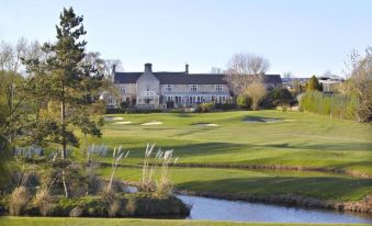 a large white building is situated in a serene golf course with a well - maintained golf course at Horsley Lodge