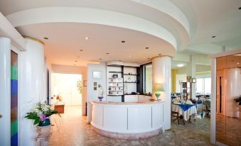 a hotel lobby with a white reception desk and chairs , as well as a dining table and chairs at Hotel Florence