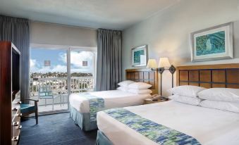 a hotel room with two beds , white bedding , and large windows offering views of the city at Aquarius Vacation Club at Dorado del Mar