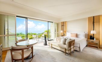 a luxurious hotel room with a large bed , a couch , and a dining table in the living area at Halekulani Okinawa