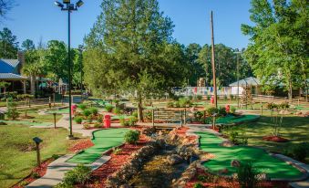 a miniature golf course surrounded by trees , with a water feature in the center of the course at Holiday Inn Club Vacations Villages Resort Lake Palestine