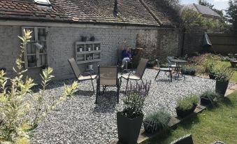 a backyard with a small yard , featuring a small patio area surrounded by potted plants and chairs at The Ardingly Inn