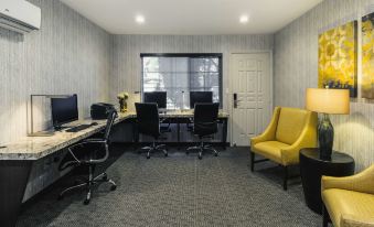 a room with two computer desks , a chair , and a yellow armchair , all set up for work or entertainment at Best Western Plus Carriage Inn