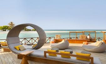 a wooden deck with lounge chairs and a table overlooking the ocean , creating a relaxing atmosphere at Lux* South Ari Atoll