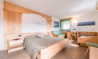 a cozy bedroom with a large bed , wooden furniture , and a dining area near the window at Hotel Alpino