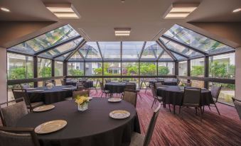 a large room with tables and chairs , a vase of flowers , and multiple skylights in the ceiling at Courtyard Lincroft Red Bank