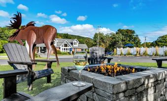 a large metal horse statue in the foreground , with a dining table and chairs set up near a fire pit at Top Notch Inn