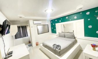 a modern bedroom with a white bed , blue and green accent wall , and a flat - screen tv mounted on the wall at Sirasit 999 Mansion