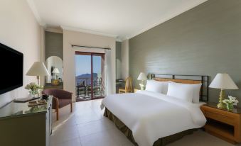 a large , well - made bed is in a bedroom with a sliding glass door leading to a balcony at Grand Mercure Petra