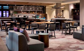 a modern lounge area with various seating options , including couches and chairs , as well as a bar area at Courtyard Schenectady at Mohawk Harbor