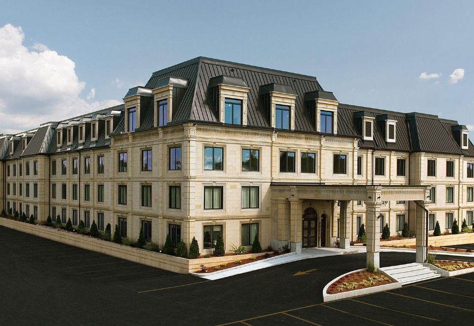 a large , elegant building with a gray roof and multiple windows is shown in the image at Hotel Brossard
