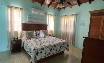 a spacious bedroom with a large bed , wooden furniture , and a ceiling fan , under a sloping ceiling at Ocean View Villas