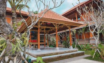 a large wooden gazebo surrounded by lush greenery , with a person standing in front of it at Ubud Hotel & Cottages