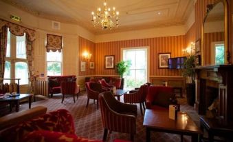a large room with multiple couches and chairs , creating a comfortable and inviting atmosphere for meetings or gatherings at Coulsdon Manor Hotel and Golf Club