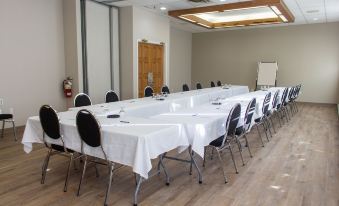 a large conference room with long tables and chairs , a projector screen , and a whiteboard at Rodd Grand Yarmouth