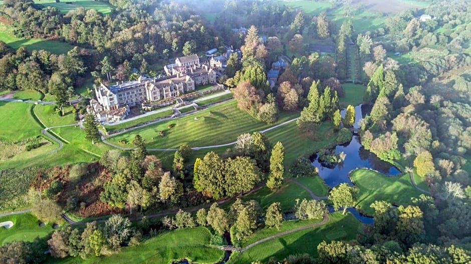 aerial view of a golf course surrounded by lush greenery , including trees , bushes , and grass at Bovey Castle