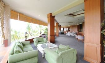 a spacious , well - lit living room with multiple couches and chairs arranged in an open space at Grand Elty Singgasana Hotel