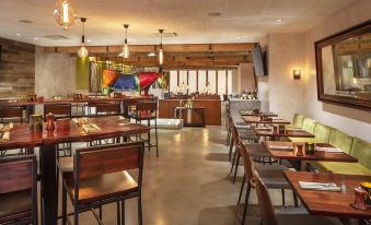 a modern restaurant with wooden tables and chairs , a bar area , and a colorful painting on the wall at Hilton San Francisco Union Square