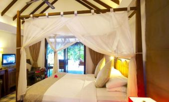 a luxurious bedroom with a large bed draped in white sheets and a canopy over it , creating a cozy atmosphere at Medhufushi Island Resort