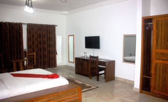 a modern bedroom with a wooden bed , desk , and tv , along with a brown curtain and white walls at Ibisa Hotel