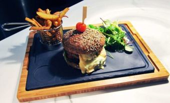 a wooden tray with a burger and fries , accompanied by a glass of water on a dining table at Logis Golfe Hotel