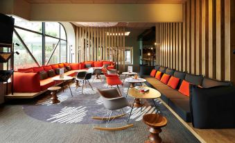a modern lounge area with red and gray furniture , wooden furniture , and large windows at Ibis Strasbourg Centre Historique