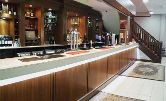 a bar with wooden cabinets and a silver faucet , surrounded by tiled flooring and a staircase at Skylark Hotel