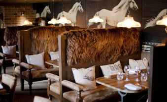 a restaurant with wooden tables and chairs , flanked by large horse sculptures on the wall at The White Horse