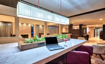a laptop is open on a table with chairs and plants in the background , in a room with pendant lights at Courtyard Hampton Coliseum Central