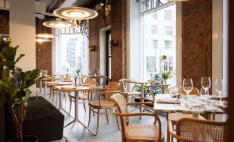 a restaurant with wooden tables and chairs , large windows , and hanging lights , giving it a cozy and inviting atmosphere at Radisson Blu 1919 Hotel Reykjavik