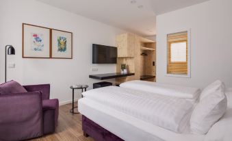 a modern hotel room with white walls , wooden floors , and a large bed , along with a dining area and bathroom at Hotel Central