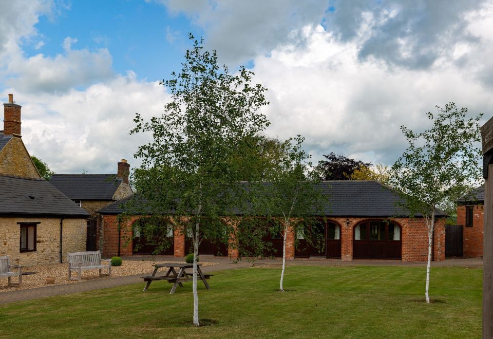 a brick building with a covered porch and a picnic area in front of it at Church Farm Lodge