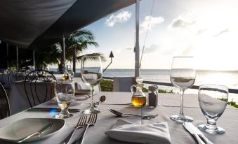a table is set with silverware , wine glasses , and napkins on an outdoor patio overlooking the ocean at The Palms Resort